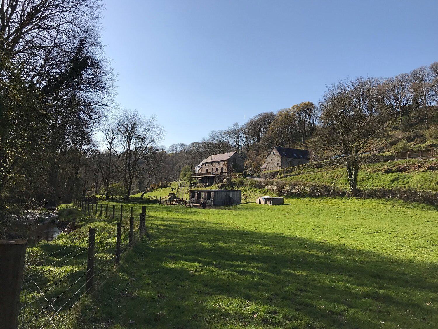 A rural landscape with a large house, a barn, and a fenced field.
