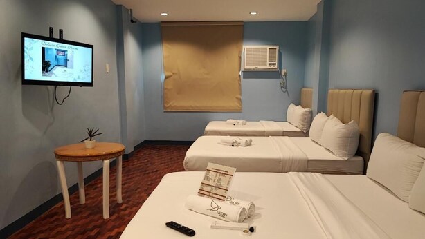 A hotel room with two beds, a TV, a small table, and a window with a blind. - Glory Hotel Cubao (Quezon City)