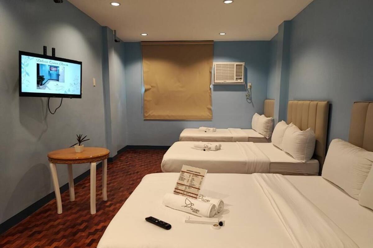 Une chambre d’hôtel avec deux lits, une télévision, une petite table et une fenêtre avec un store.