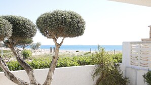 Une vue sur la côte, avec un mur blanc, deux arbres taillés en forme de sphère et un jardin rocheux.