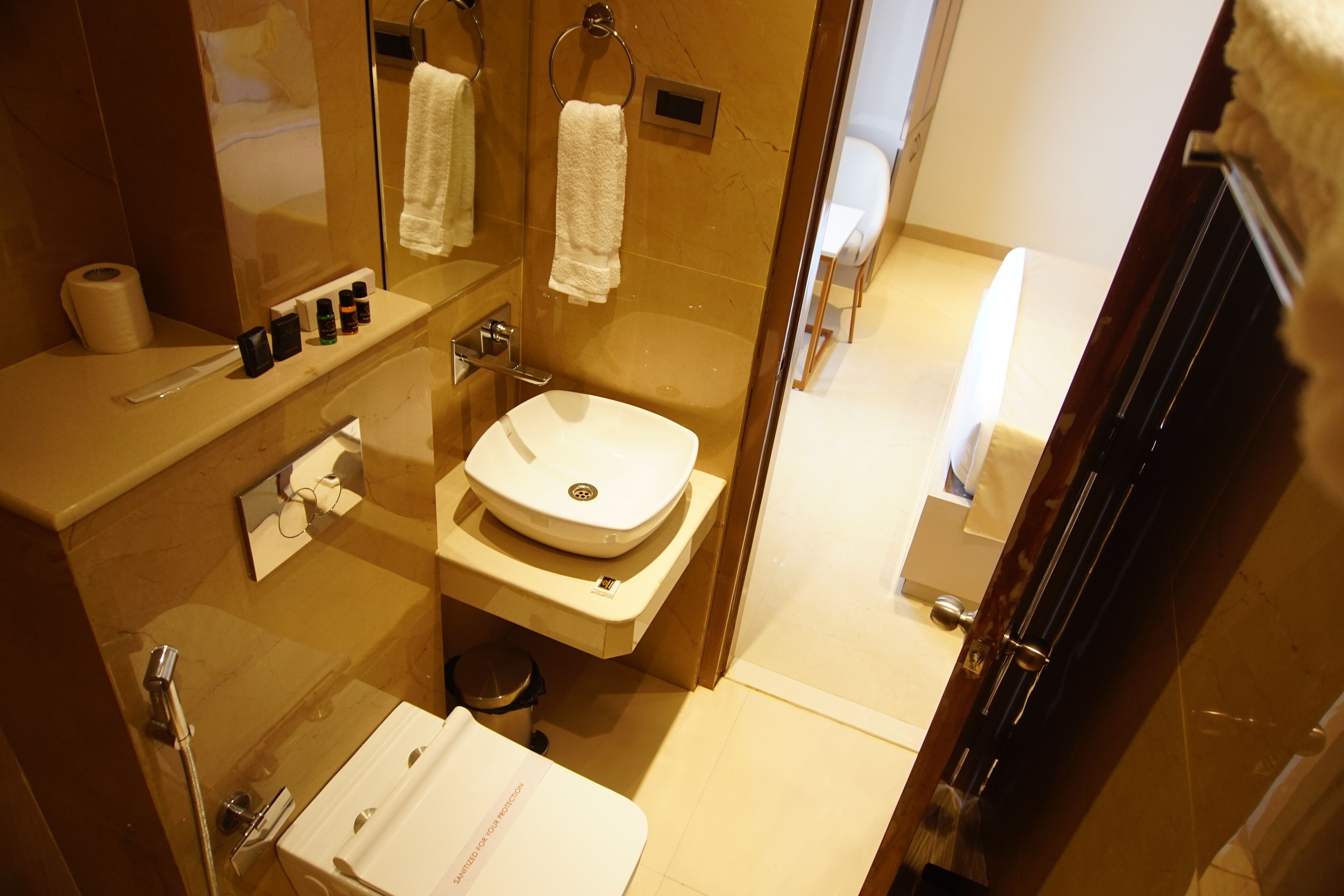 A modern bathroom with a sink, mirror, and towel rack.