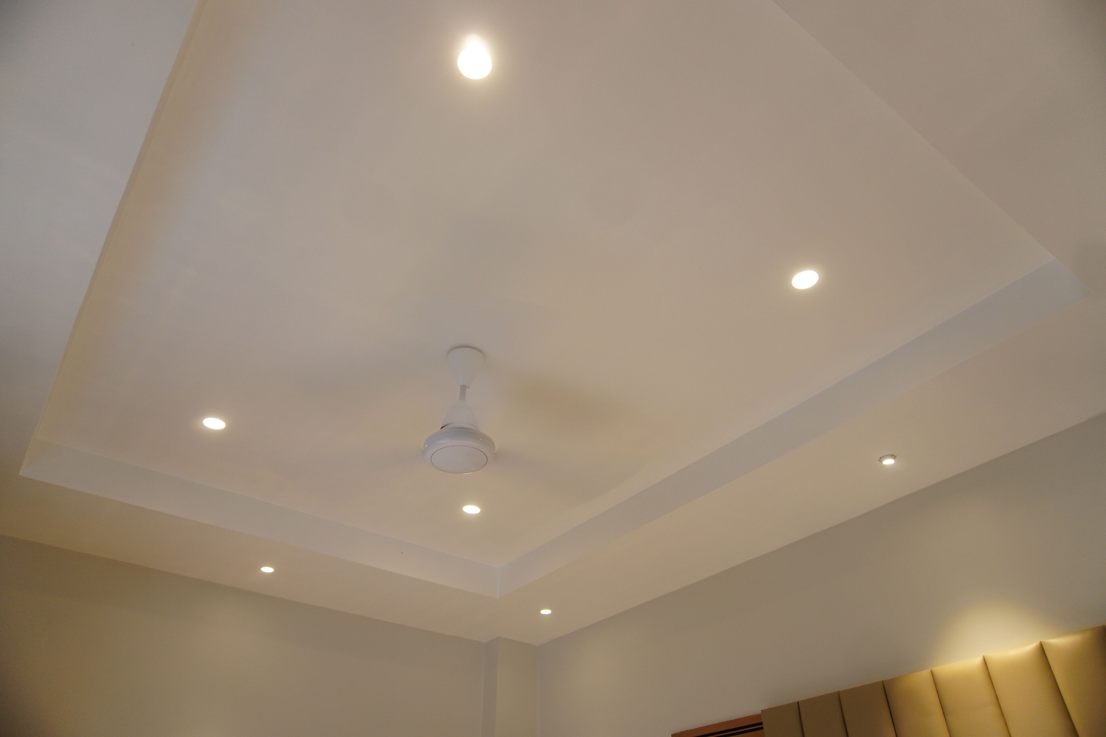 A room with a white ceiling, recessed lighting, and a ceiling fan.