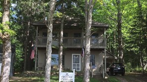 A two-story building with a porch and a sign that reads "The Felker's Cottage." - Felker's Cottage: Fall Color Getaway | Lakefront Cottage Near Tunnel of Trees (Vanderbilt)