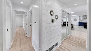 Un interior moderno con un pasillo que conduce a una habitación con un espejo grande y apliques decorativos en la pared.