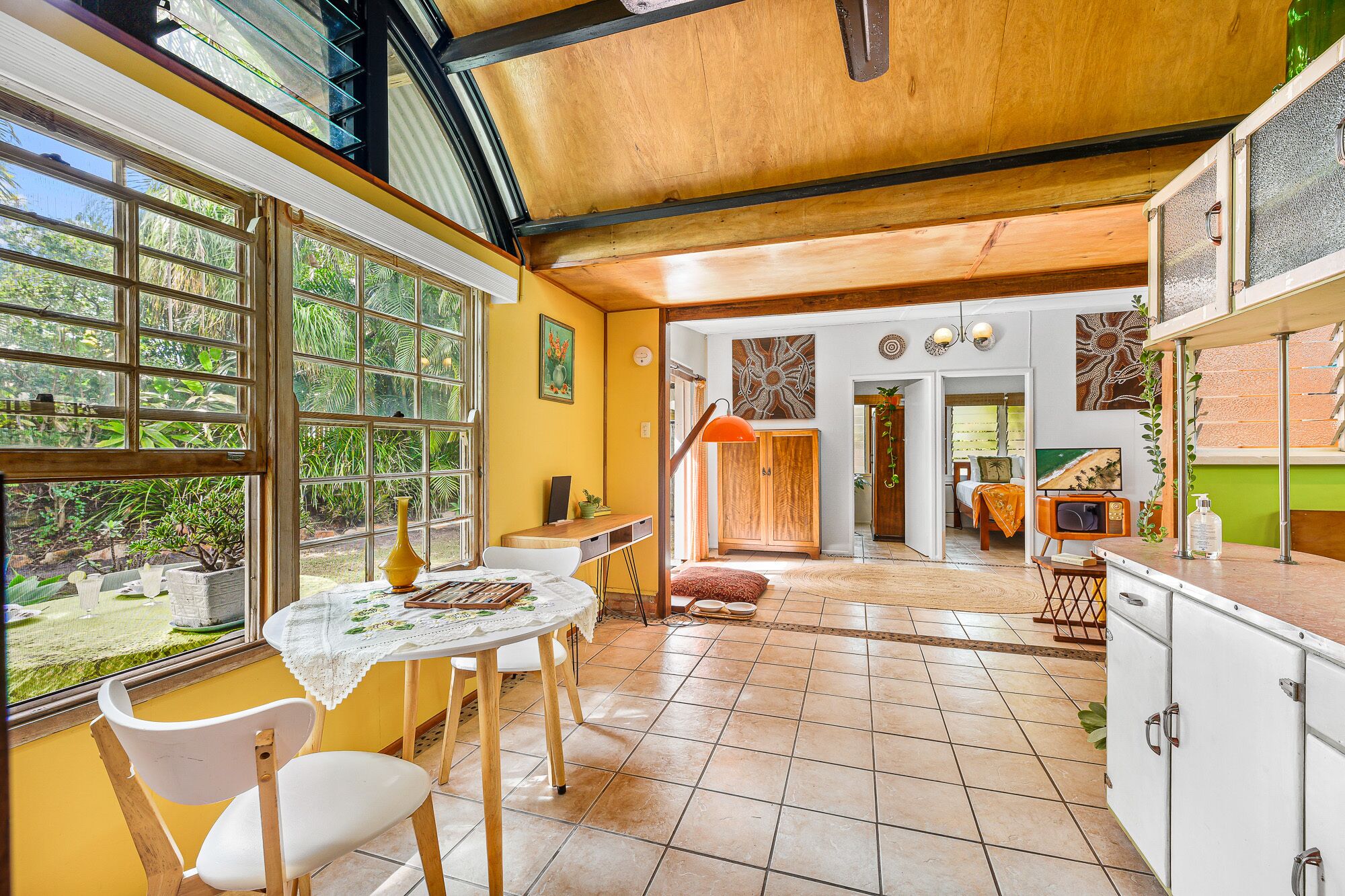 A spacious kitchen with a dining area, large windows, and a view of greenery.