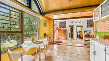 A spacious kitchen with a dining area, large windows, and a view of greenery.