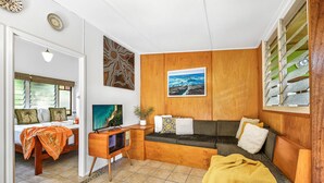 Una habitación acogedora con una cama, un escritorio de madera, un sofá y un televisor.