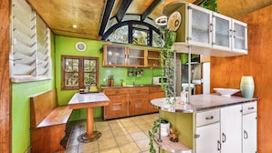 Una cocina con paredes verdes, armarios de madera y piso de baldosas.