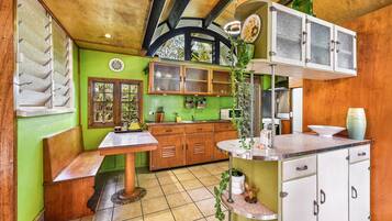 A kitchen with green walls, wooden cabinets, and a tiled floor.