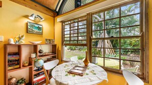 Una habitación con una mesa redonda, sillas, una estantería y una ventana que da a zonas verdes.