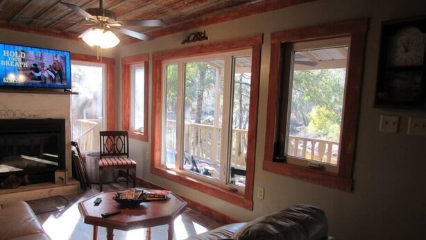 A living room with a fireplace, a television, and large windows. - On the Riverbend Cabin (Claxton)