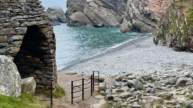 Une construction en pierre située sur la côte, avec un étroit passage menant à une plage.