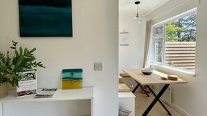 Une cuisine moderne avec une table en bois, un luminaire suspendu et une fenêtre donnant sur les arbres.