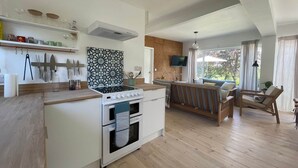 A modern kitchen with a built-in stove, oven, and microwave. There is a dining area with a wooden table and chairs, and a large window providing a view of the outdoors.