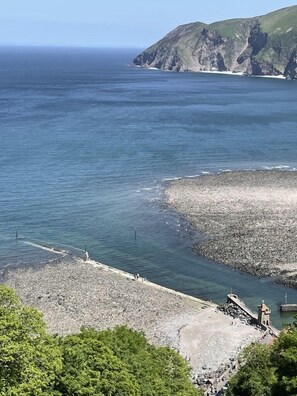 A coastal landscape with a rocky shoreline, a pier, and a view of the sea and cliffs. - Whitebeam Cottage, Moor and Sea, beautiful views of Exmoor (Lynton)