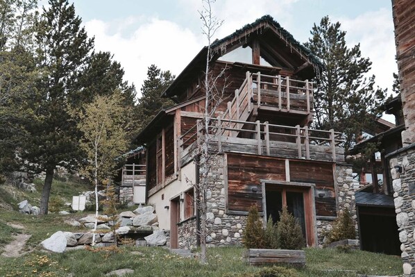A rustic cabin with a stone facade, wooden balcony, and a stone entrance. - Chalet Mintaka Collection Greniers d'Alpages (BOLQUÈRE FONT-ROMEU)