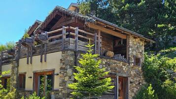 Una cabaña rústica con fachada de piedra, balcones de madera y tejado de paja.