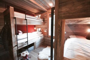 A compact, wooden cabin-style room with bunk beds, a small rug, and a dog bed.