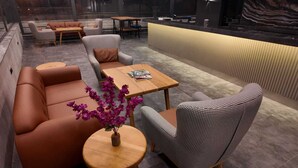 Un espace de détente moderne avec des canapés en cuir, des fauteuils à motifs pied-de-poule et une table basse en bois.