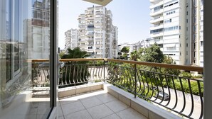 Un balcon doté d’une rambarde en métal, donnant sur un quartier résidentiel avec de grands immeubles.