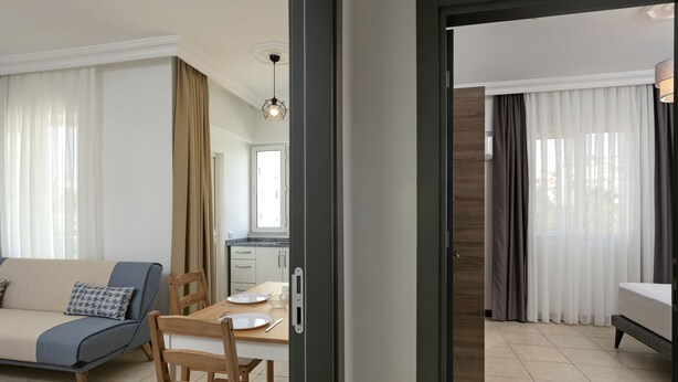 Un salon moderne avec un canapé, une table à manger et des chaises. On aperçoit un coin cuisine à travers une porte ouverte.