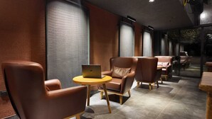 Un espace détente moderne avec des fauteuils en cuir et une table ronde, agrémenté d’un ordinateur portable.