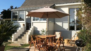 A house with a patio, outdoor furniture, and a barbecue grill.