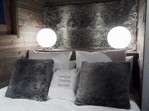 Una cama con ropa blanca y dos apliques de pared redondos.
