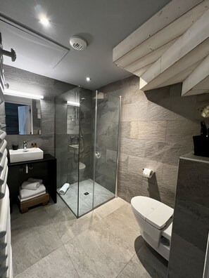 Une salle de bain moderne avec une douche à parois de verre, un lavabo blanc et des toilettes.