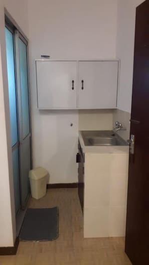 Compact kitchen area with a countertop, sink, and cabinets.