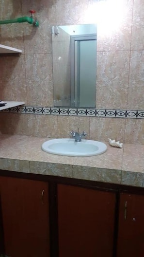 Un baño con lavamanos, espejo y paredes de azulejos.