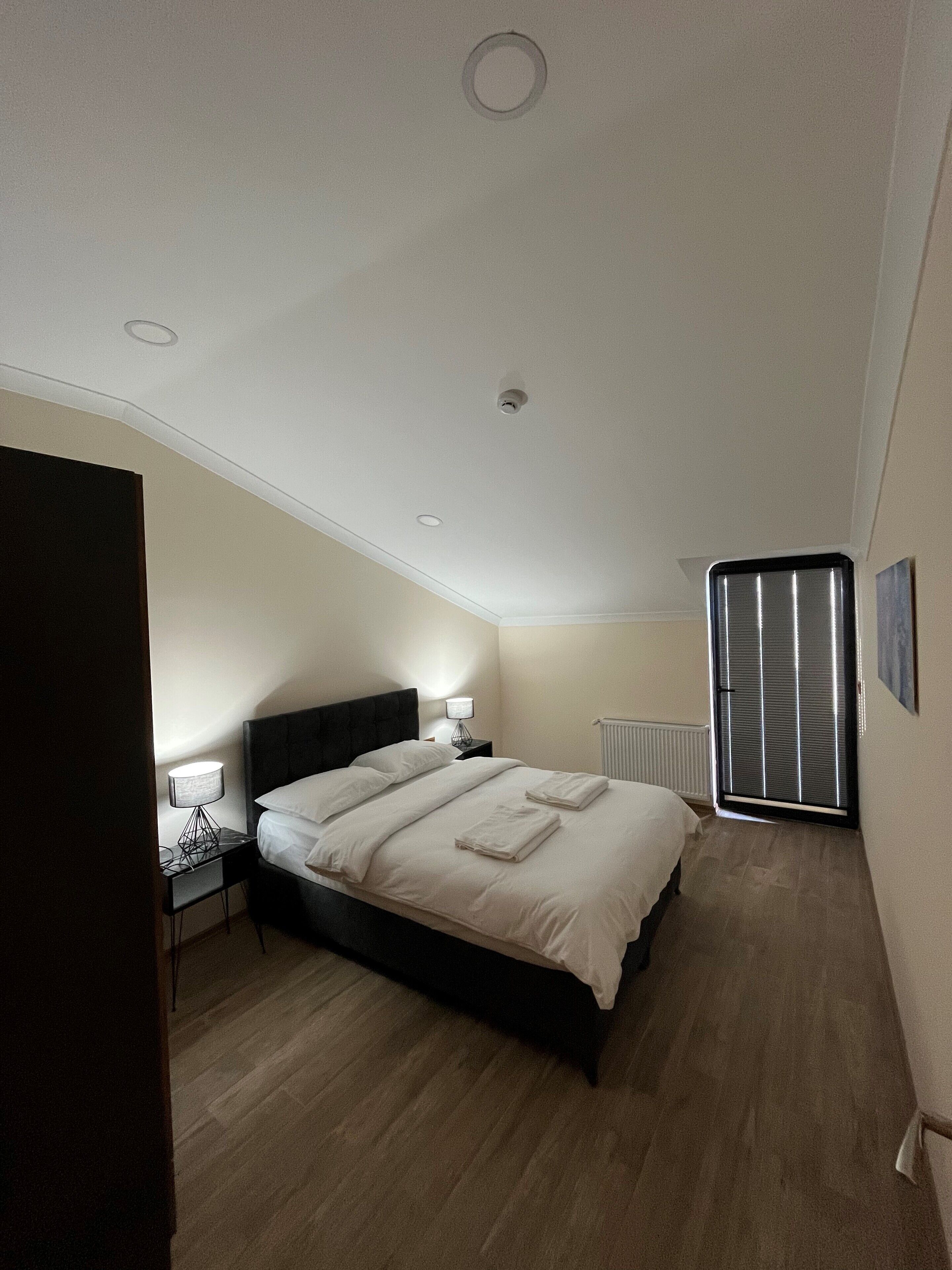A bedroom with a bed, bedside tables, a lamp, and a radiator.