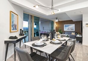Ein moderner Essbereich mit einem großen Tisch für sechs Personen, einer Couch und Blick auf die Stadt.