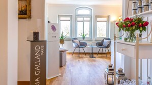 Un intérieur moderne comprenant un coin repas, un meuble blanc orné d’un vase de fleurs et un tableau encadré accroché au mur.