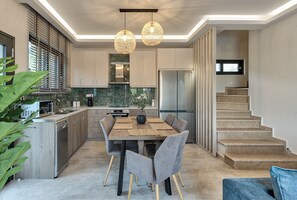 A modern kitchen with a dining area, built-in appliances, and a staircase.
