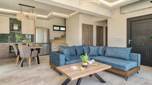 Ein modernes Wohnzimmer mit einem blauen Sofa, einem Holztisch und einem Essbereich mit Tisch und Stühlen.
