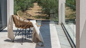 Ein Balkon mit Korbstühlen und einem Tisch mit Blick auf einen Weinberg.