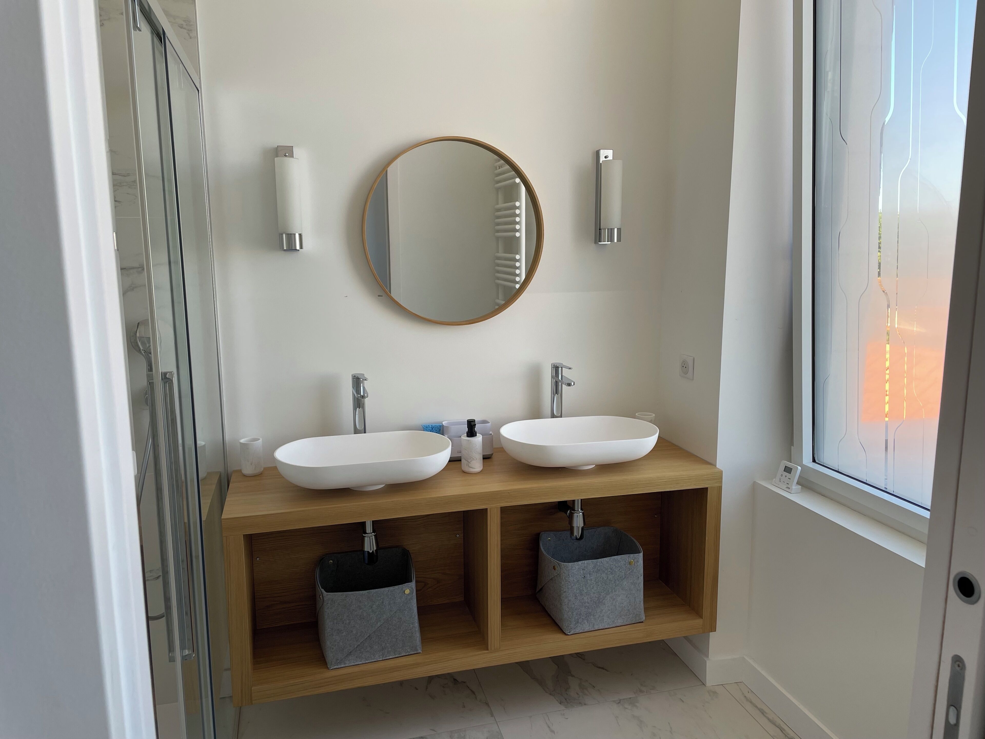 A modern bathroom with two sinks, a mirror, and a shower enclosure.
