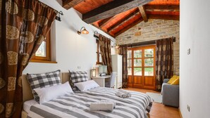 A bedroom with a large bed, a desk, and a view of the outdoors.