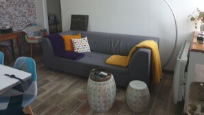 A living room with a grey sofa, patterned cushions, a small coffee table, and a brick wall.