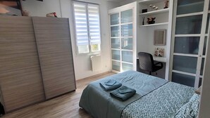 A bedroom with a bed, a wardrobe, a desk, a chair, and a ceiling fan.
