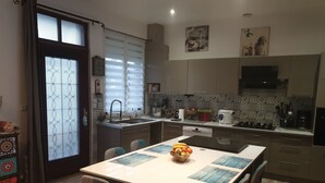 A modern kitchen with a dining area, featuring a central island, a sink, and a stove.