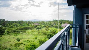 A balcony with a view of a green landscape and distant houses. - Stay.Plus Nanyuki Apartment (Nanyuki)