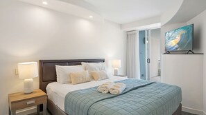 Hotellihuone, jossa on sänky, yöpöydät, lamppu, taulu ja näkymä ulos.