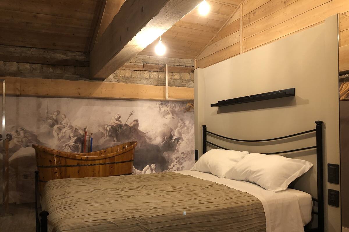A bedroom with a bed, a wooden boat, and a mural on the wall.
