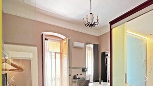 A hotel room with a bed, a desk, a chair, a chandelier, and a patterned floor. - Residenze Romano & SPA hotel diff. RED (Foggia)