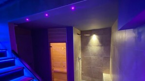 A modern bathroom with a shower, a wooden door, and a staircase with blue lighting. - Residenze Romano & SPA hotel diff. RED (Foggia)