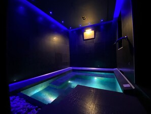 Uma área de spa moderna com piscina aquecida e iluminação ambiente azul.