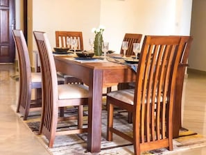 A dining area with a wooden table and chairs, a vase with flowers, and a bowl on the table.