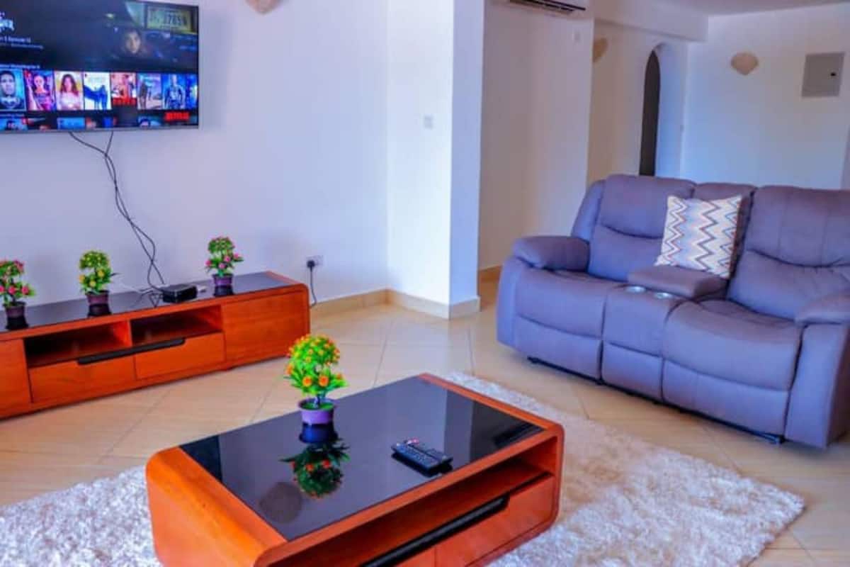 A living room with a sofa, a coffee table, and a TV mounted on the wall.